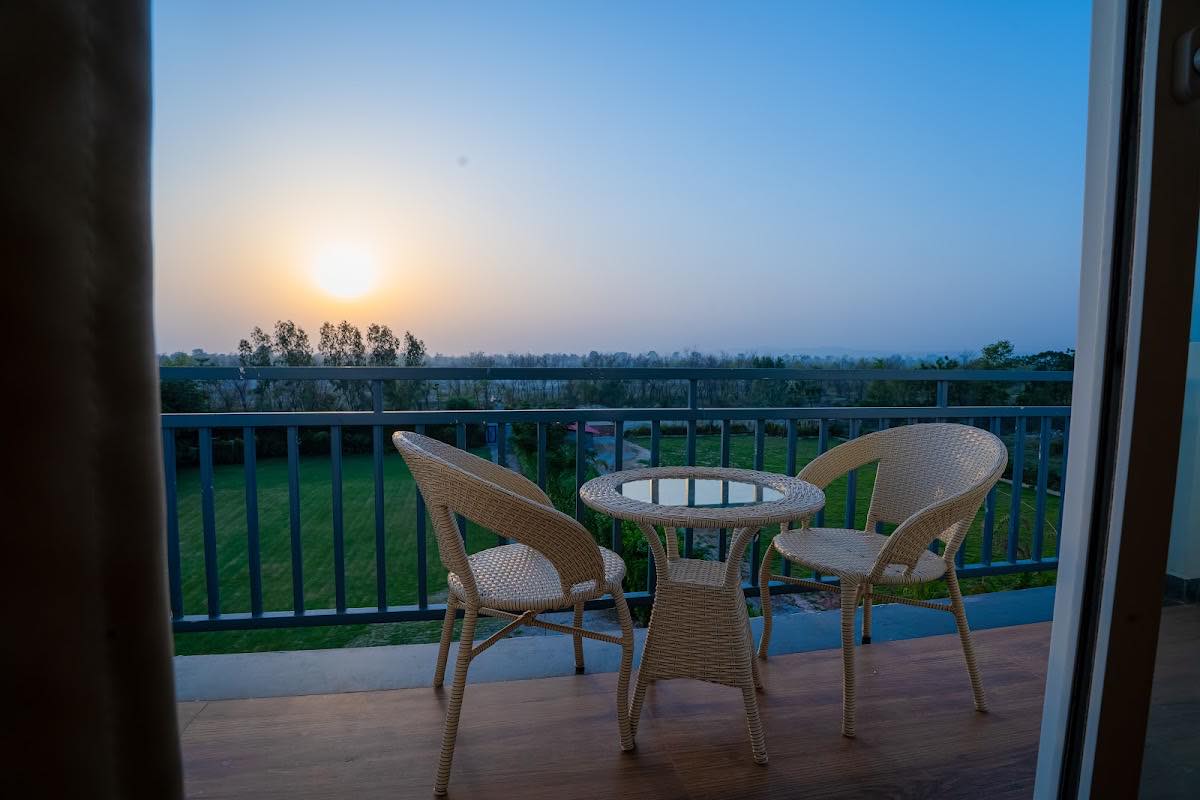 Sunrise over green fields and a line of trees, seen from a hotel balcony in Ramnagar, the gateway town for Jim Corbett National Park