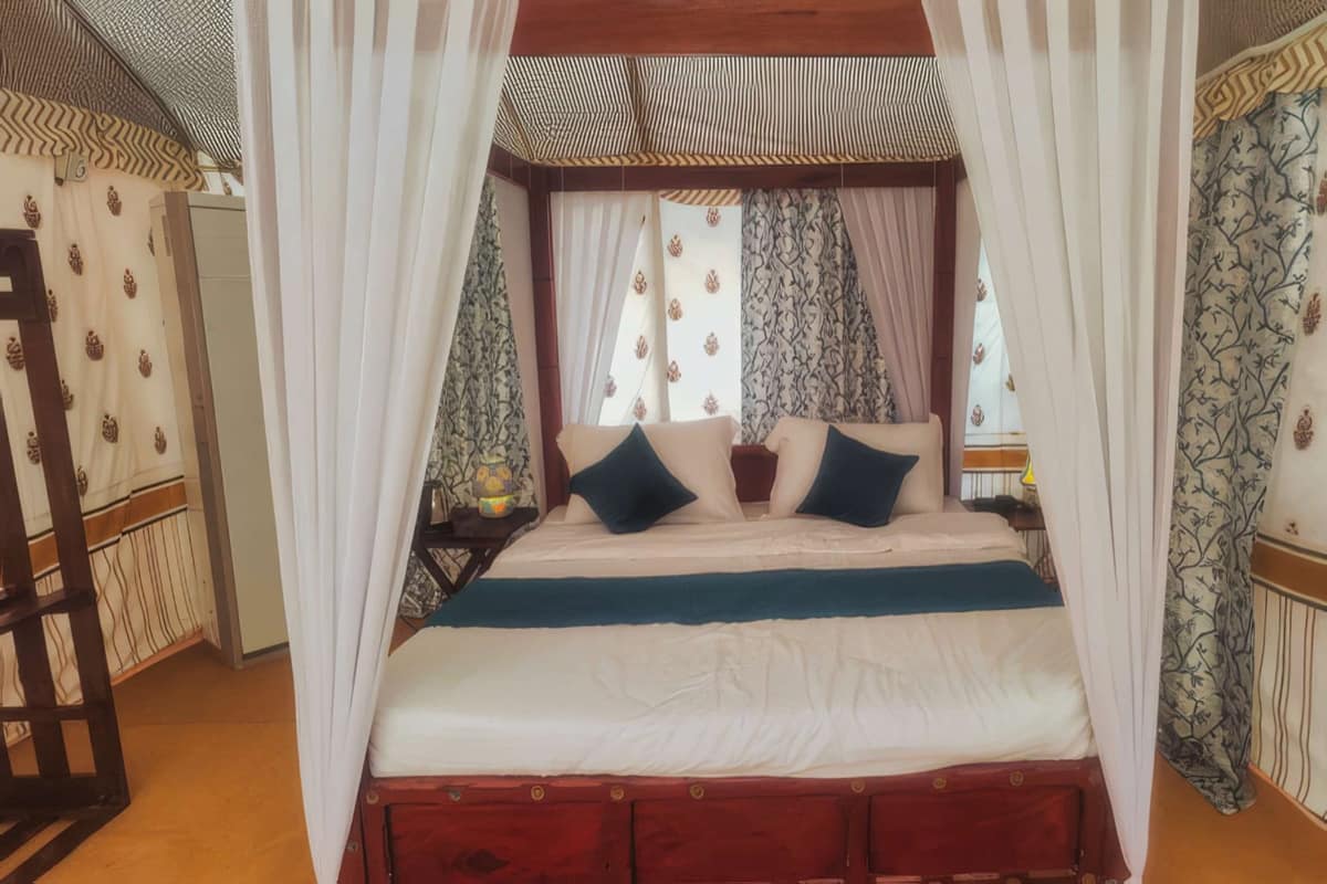 Luxury tent with a four-poster king bed at a Pulp Hotels Kumbh camp