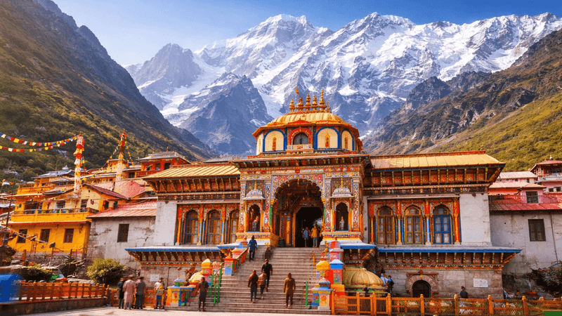 The painted facade of Badrinath temple with snow peaks behind